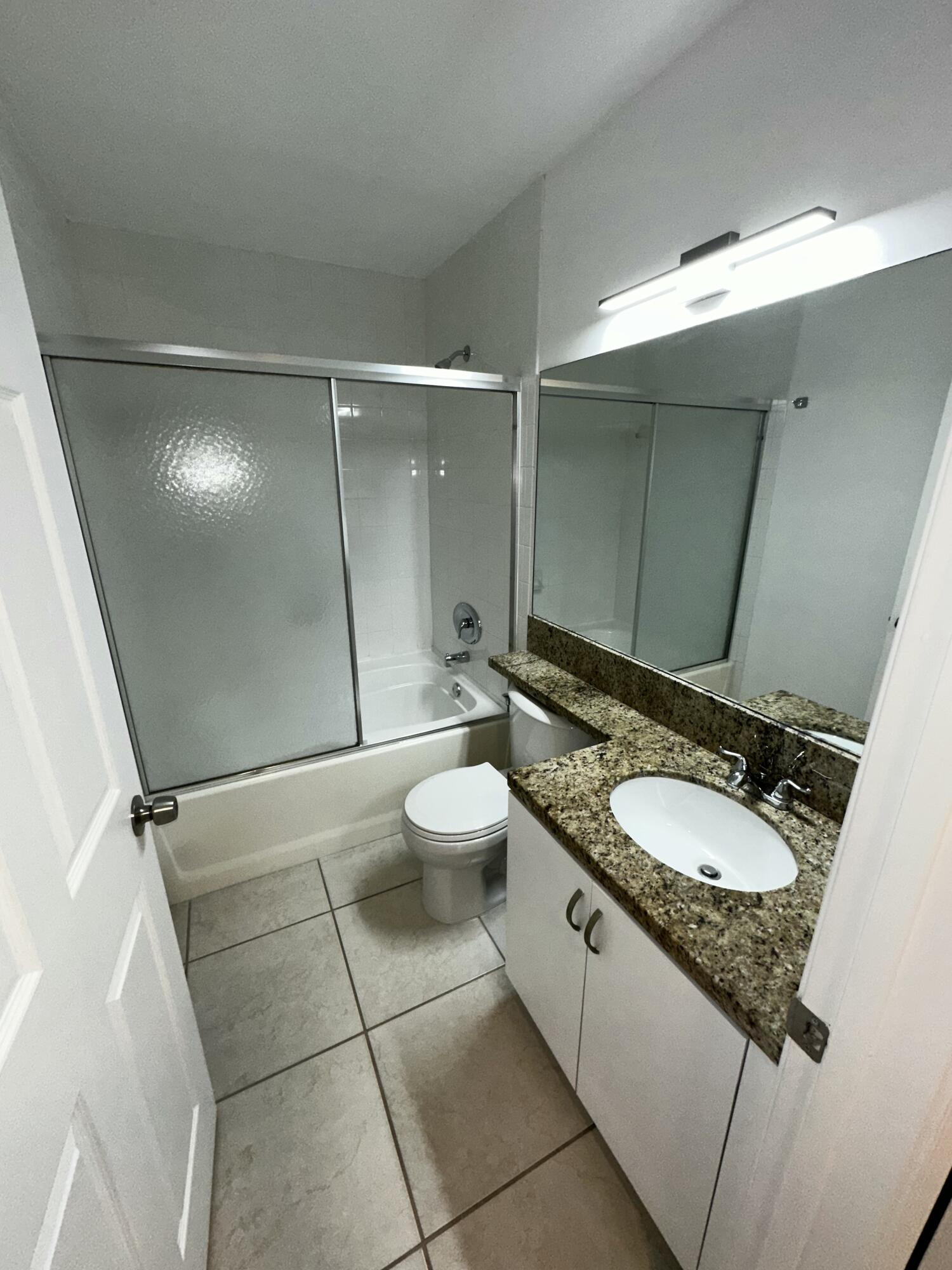 2103 Renaissance Boulevard, Unit 306 Miramar, FL 33025 - Photo 12 of 44 a bathroom with a granite countertop sink a toilet and a mirror