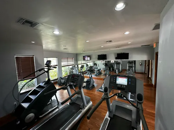 a room with gym equipment equipment wooden floor and windows