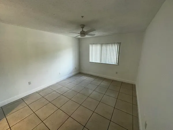 an empty room with windows and ceiling fan