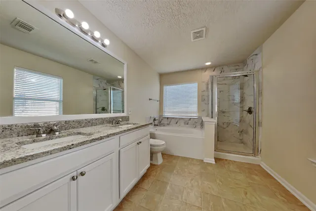 a bathroom with a granite countertop double vanity sink a large mirror a shower and a bathtub