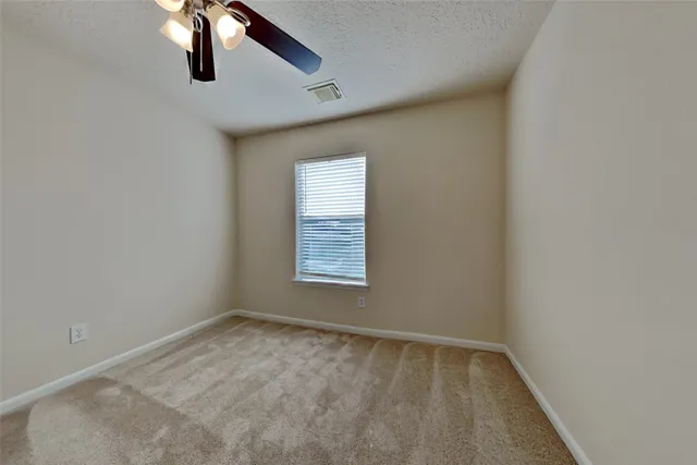 an empty room with a window and a fan