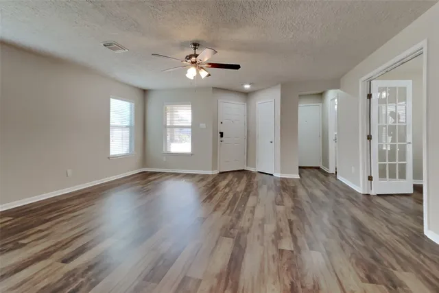 a view of an empty room with wooden floor and window