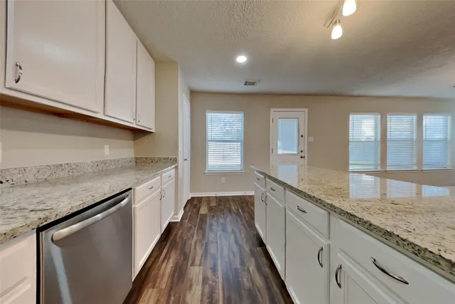 a large kitchen with granite countertop a sink and dishwasher a stove top oven with wooden floor