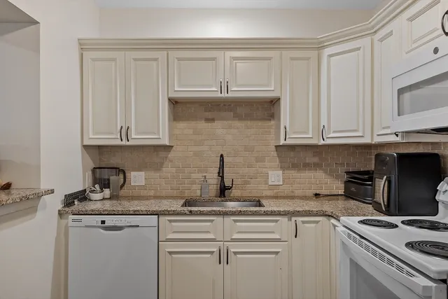 a kitchen with stainless steel appliances granite countertop white cabinets and a stove a sink