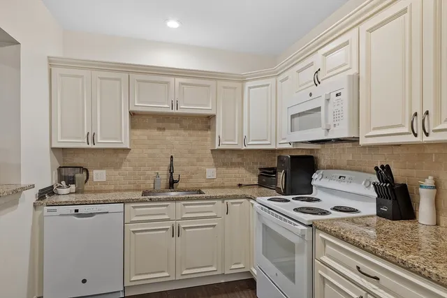 a kitchen with white cabinets sink and stove