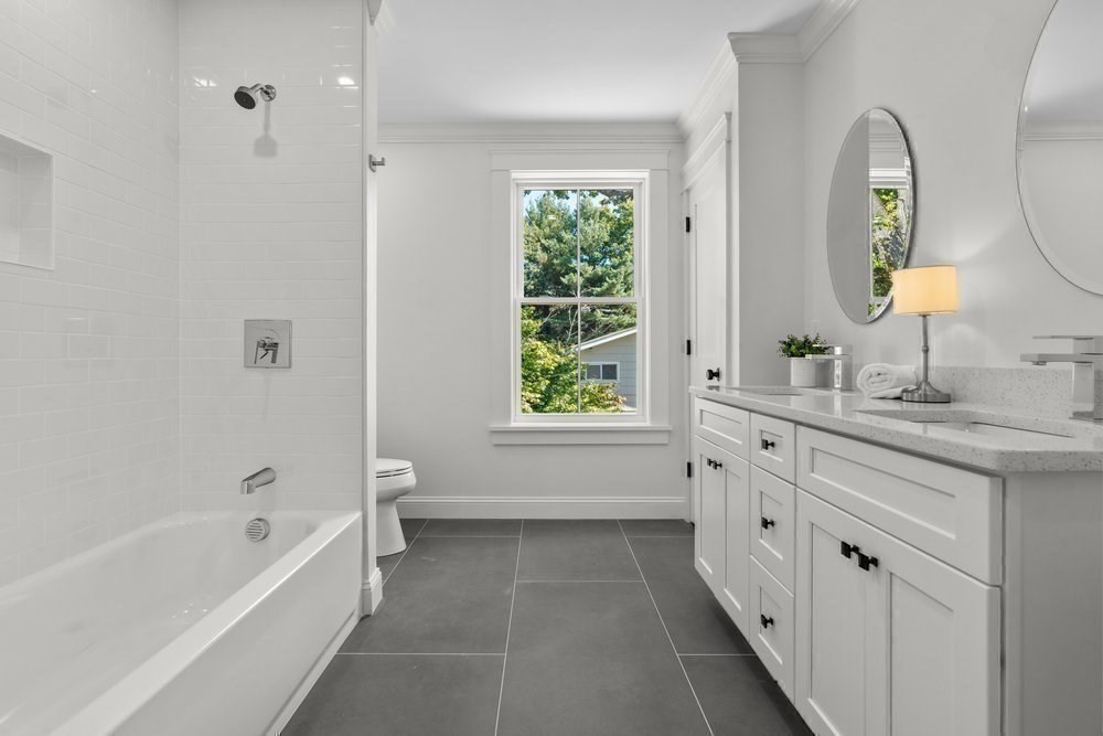22 Tyler Road Lexington, MA 02420 - Photo 29 of 37 a bathroom with a granite countertop sink a mirror a bathtub and next to a window