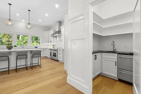 a kitchen with kitchen island a stove a refrigerator and a dining table with wooden floor