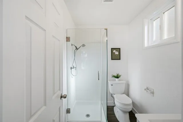 a bathroom with a granite countertop toilet a shower and a sink