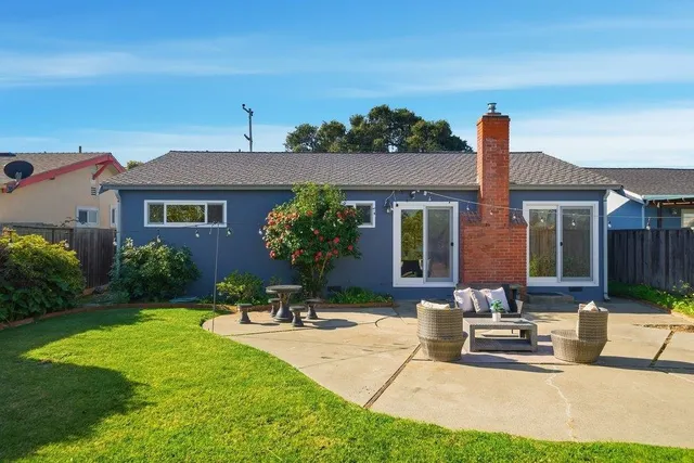a view of house with backyard and outdoor seating