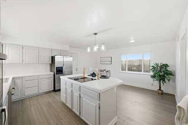 a kitchen that has a lot of white cabinets and stainless steel appliances