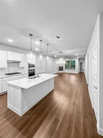 a large white kitchen with wooden floors and stainless steel appliances