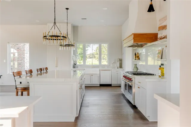 a kitchen with stainless steel appliances granite countertop a stove a refrigerator a kitchen island a dining table and chairs with wooden floor