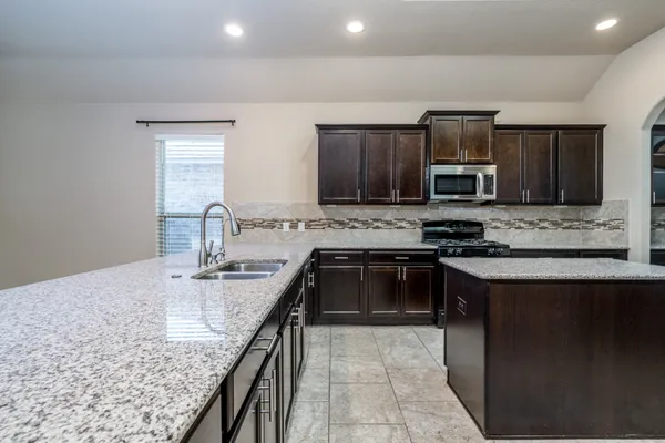a kitchen with kitchen island granite countertop a sink stove and microwave