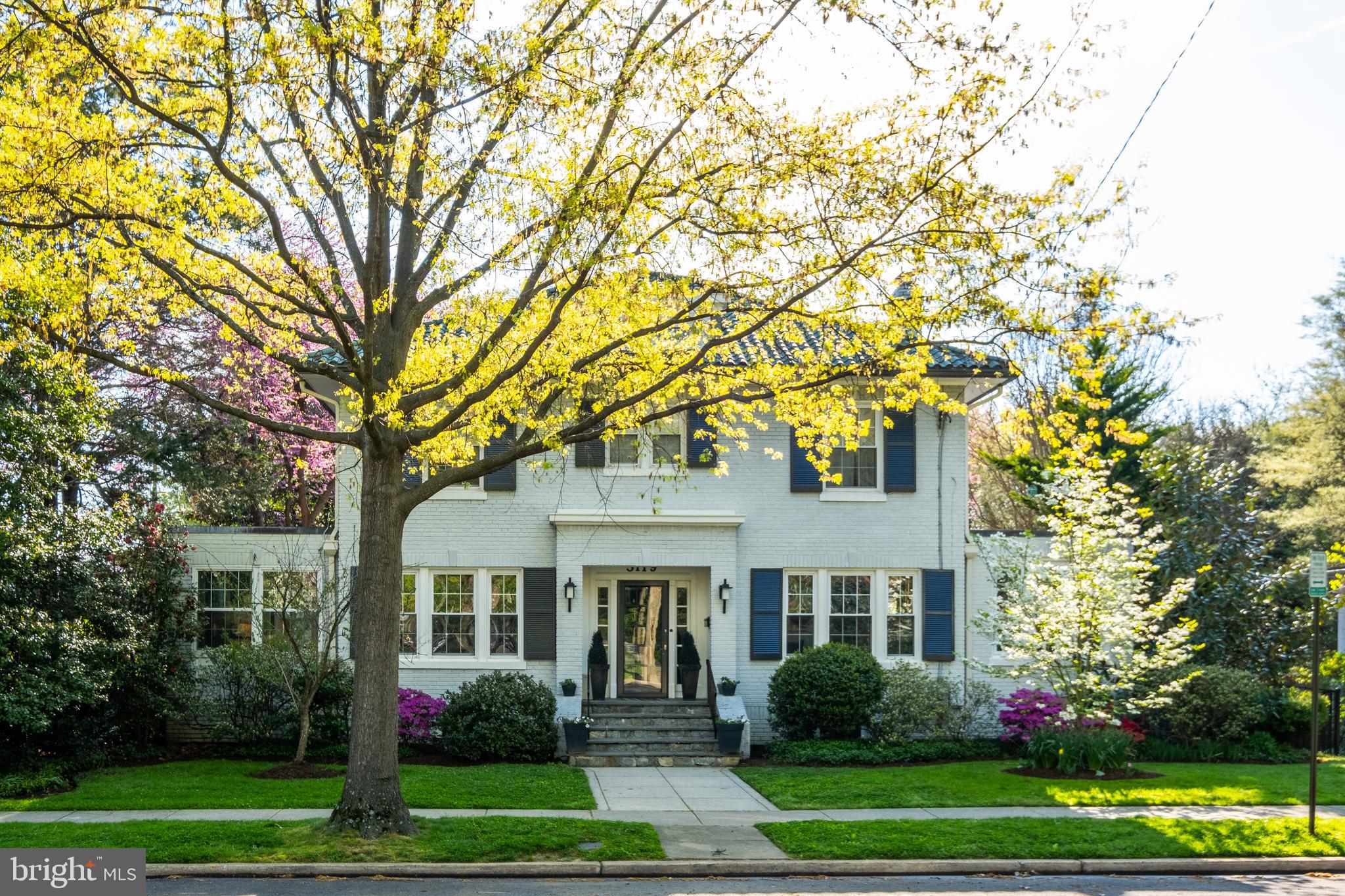 a front view of a house with garden and trees