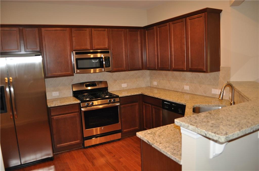 4390 Cedar Bridge Walk Suwanee, GA 30024 - Photo 3 of 14 a kitchen with granite countertop stainless steel appliances and wooden cabinets