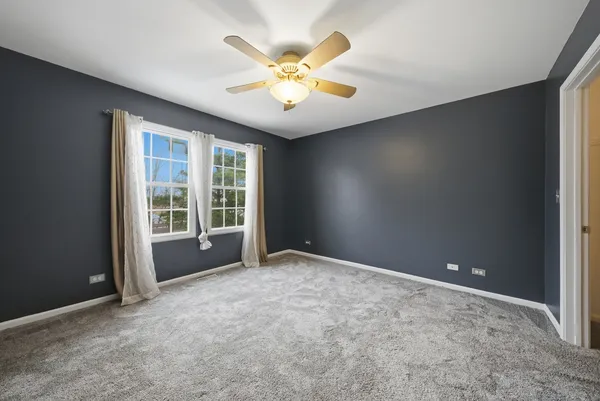 an empty room with ceiling fan and window
