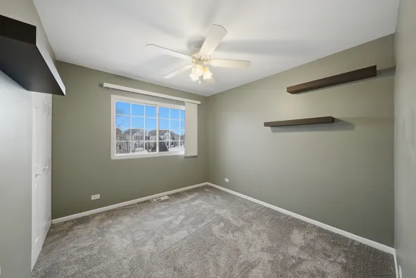 an empty room with windows and fan