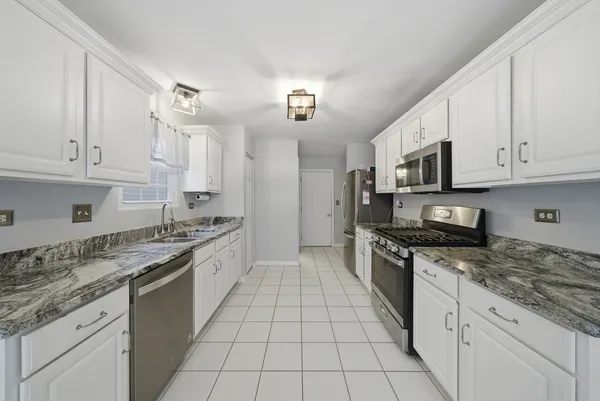 a large kitchen with granite countertop white cabinets a sink a stove a oven with white cabinets