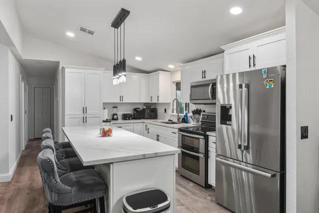 a kitchen with refrigerator a sink and chairs