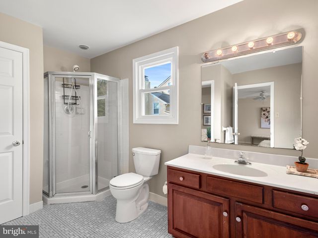 a bathroom with a toilet a sink a mirror a shower a vanity and window