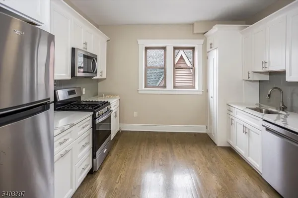 a kitchen with granite countertop a refrigerator stove top oven and sink