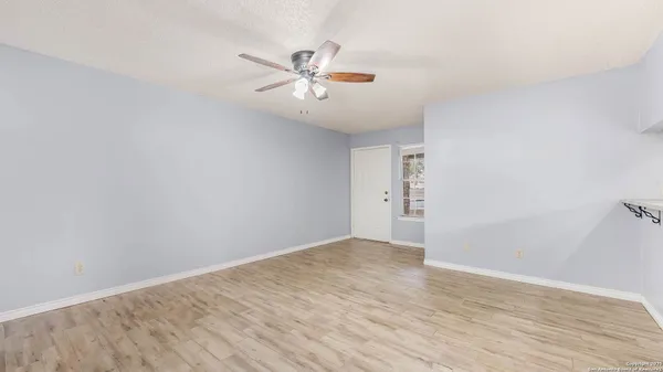 a view of an empty room with chandelier fan and wooden floor