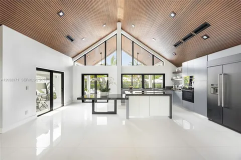 a large white kitchen with large windows and refrigerator