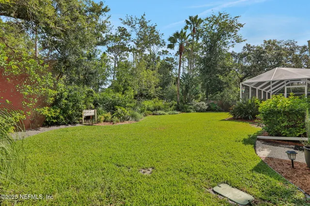 a view of a swimming pool with a yard and large trees