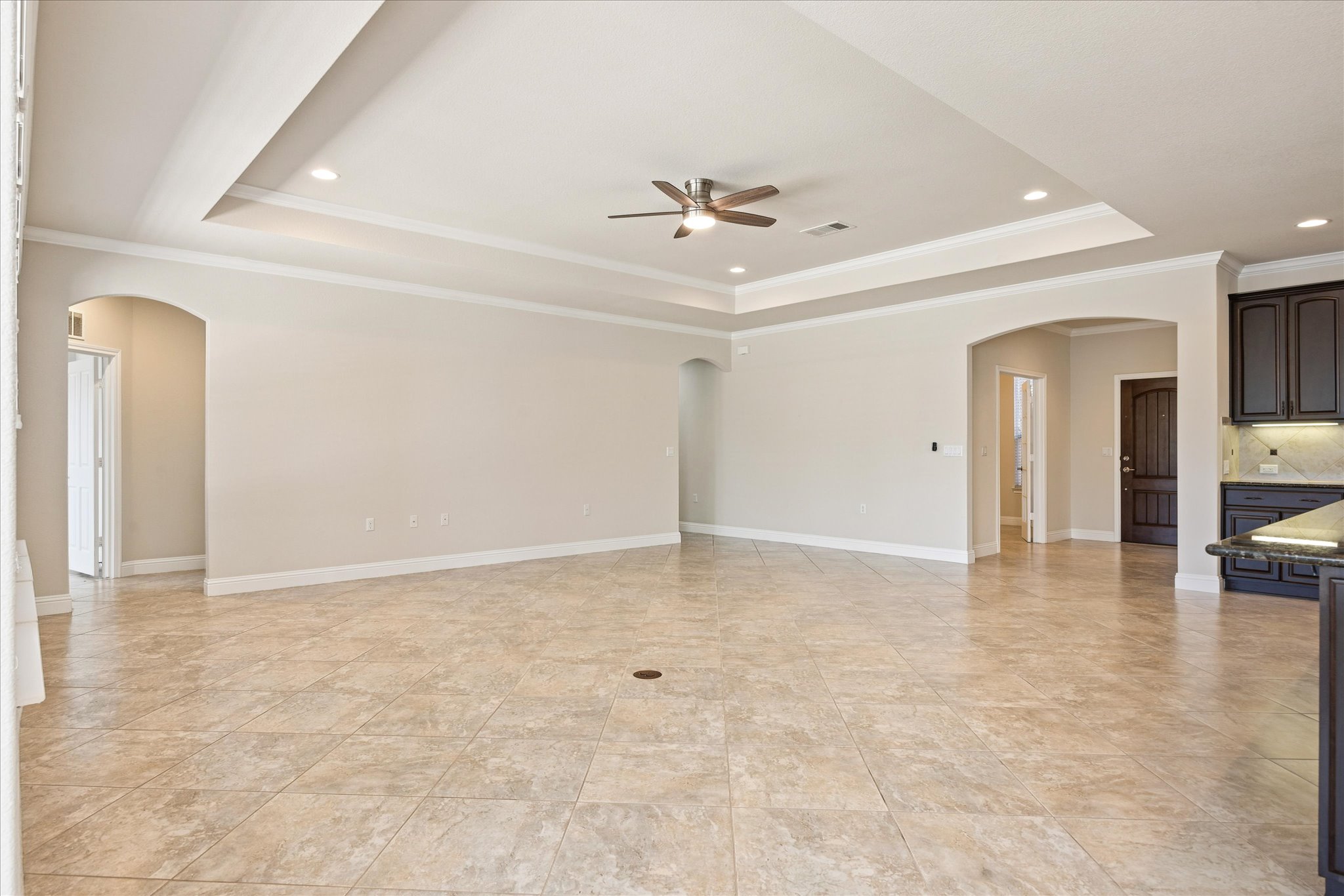 An elegant tray ceiling and durable tile flooring define this airy, open-concept living space.