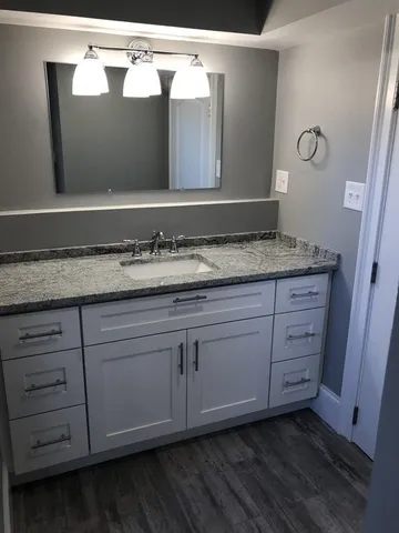 a bathroom with a granite countertop sink and a mirror