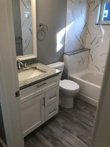 a bathroom with a granite countertop toilet a sink and a mirror