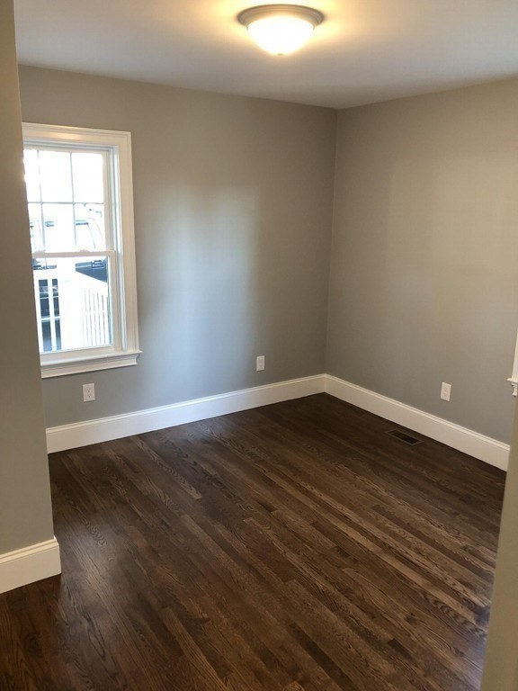 440 Central Avenue, Unit 1 Milton, MA 02186 - Photo 10 of 14 a view of an empty room with wooden floor and a window