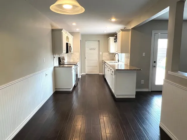 a kitchen with stainless steel appliances a refrigerator and a wooden floor