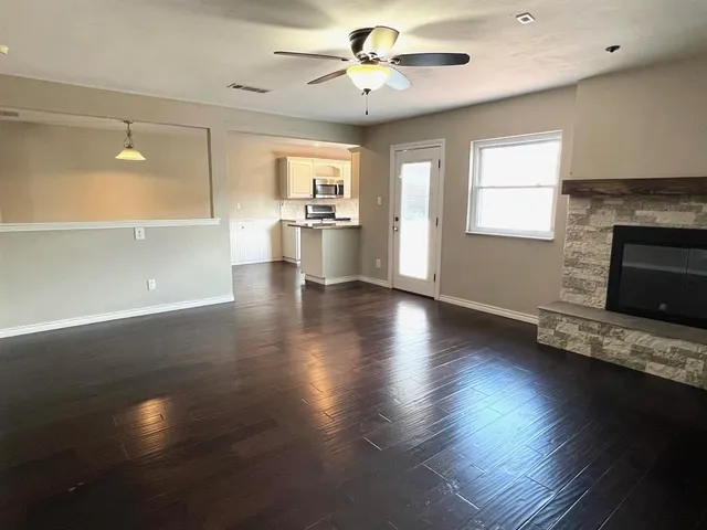 a view of empty room with wooden floor and a kitchen