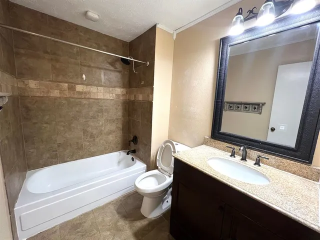 a bathroom with a granite countertop bathtub shower sink vanity mirror and toilet