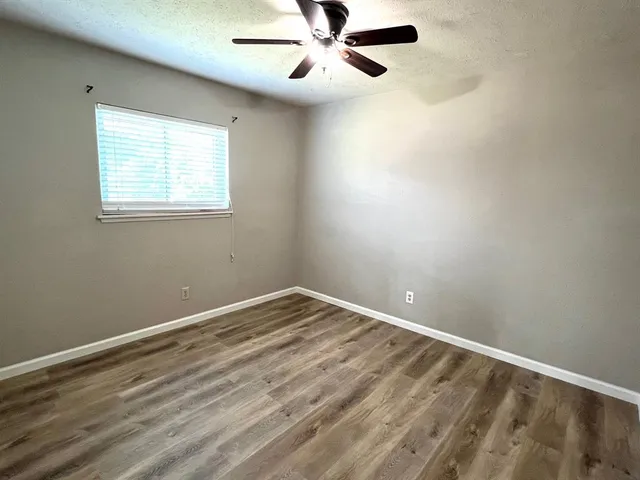 an empty room with a window and a fan