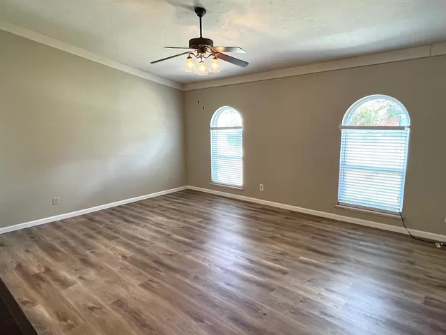 a view of empty room with wooden floor and fan