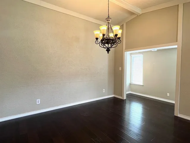 an empty room with wooden floor and chandelier