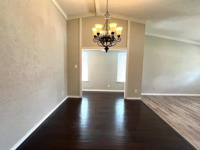 a view of a chandelier in big room with wooden floor
