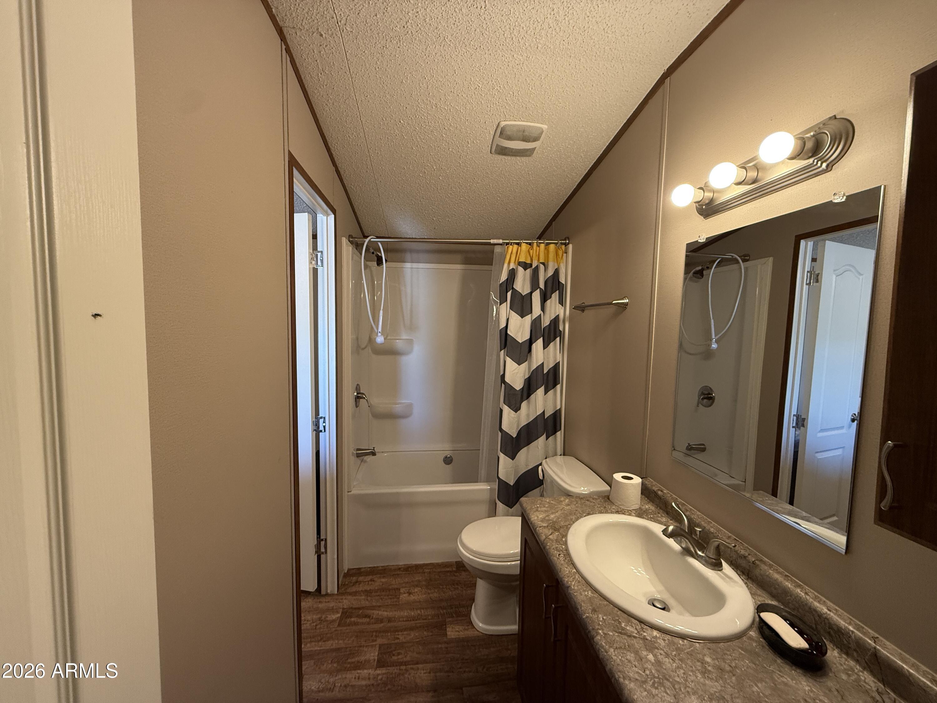 694 South Desert View Drive Apache Junction, AZ 85120 - Photo 10 of 23 a bathroom with a granite countertop sink toilet a mirror a vanity and shower