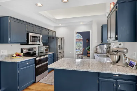 a kitchen with stainless steel appliances granite countertop a sink dishwasher stove and refrigerator with wooden floor