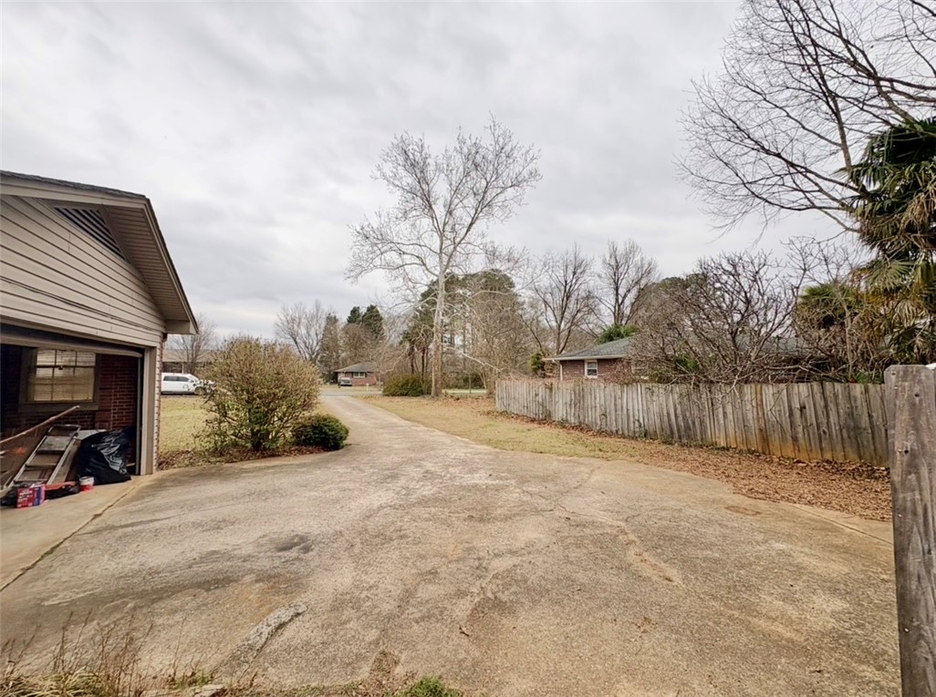 402 Loblolly Drive Anderson, SC 29625 - Photo 43 of 43 This concrete driveway leads to a home with a wooden fence and surrounding mature trees.