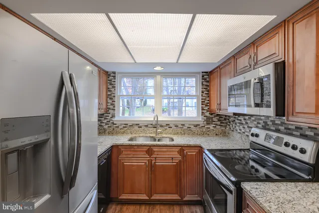 a kitchen with stainless steel appliances granite countertop a stove a refrigerator and a sink