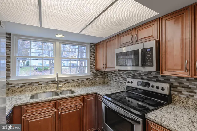 a kitchen with granite countertop a sink stove and cabinets