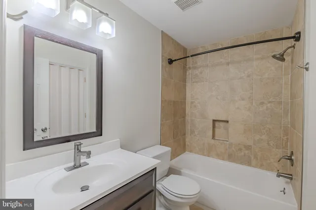 a bathroom with a bathtub shower sink vanity mirror and toilet
