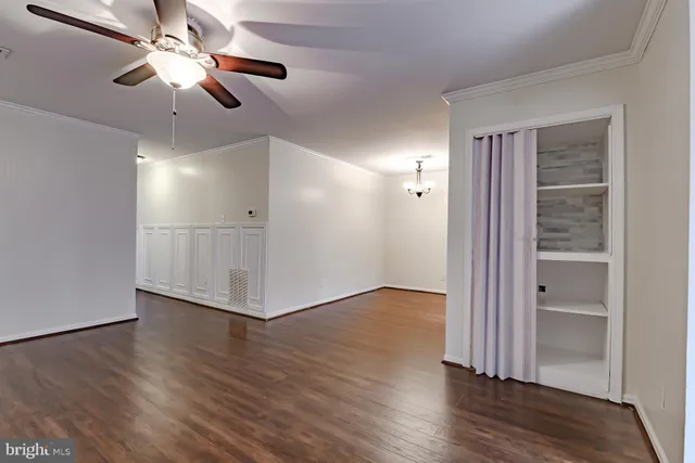 a view of an empty room with wooden floor a ceiling fan and windows