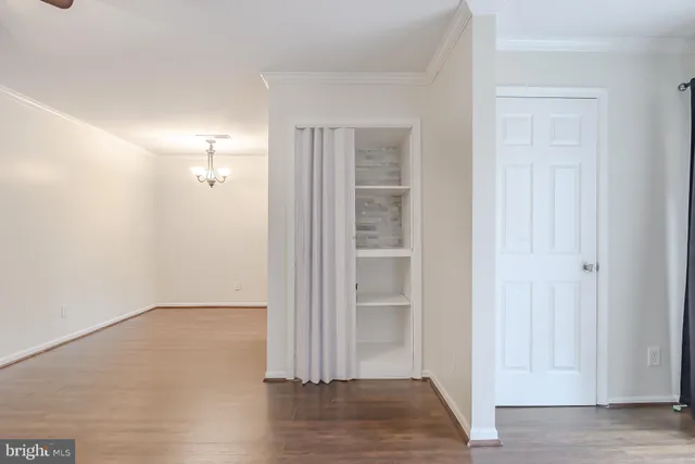 an empty room with wooden floor closet and windows