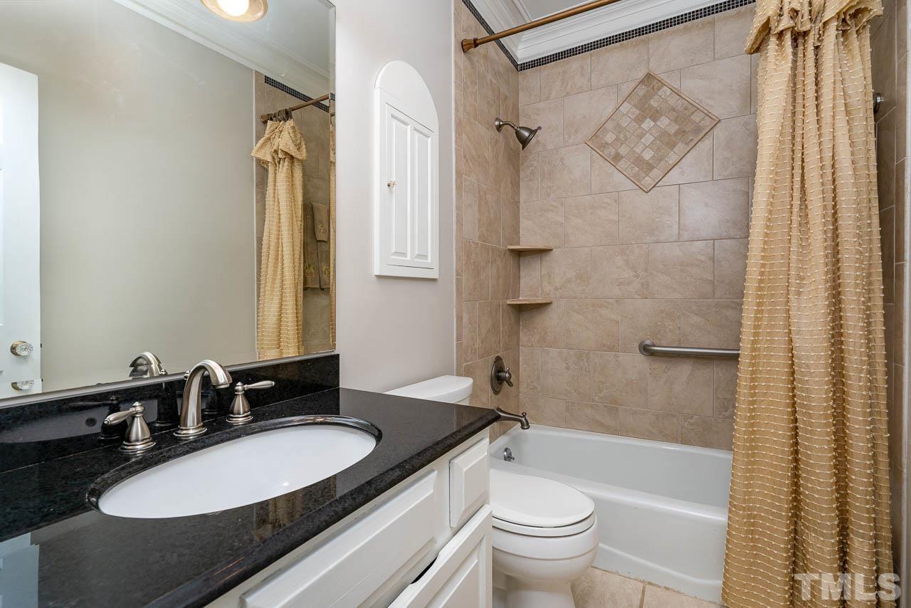 2625 Ashland Street Raleigh, NC 27608 - Photo 18 of 26 a bathroom with a granite countertop sink toilet a mirror a shower and a bathtub