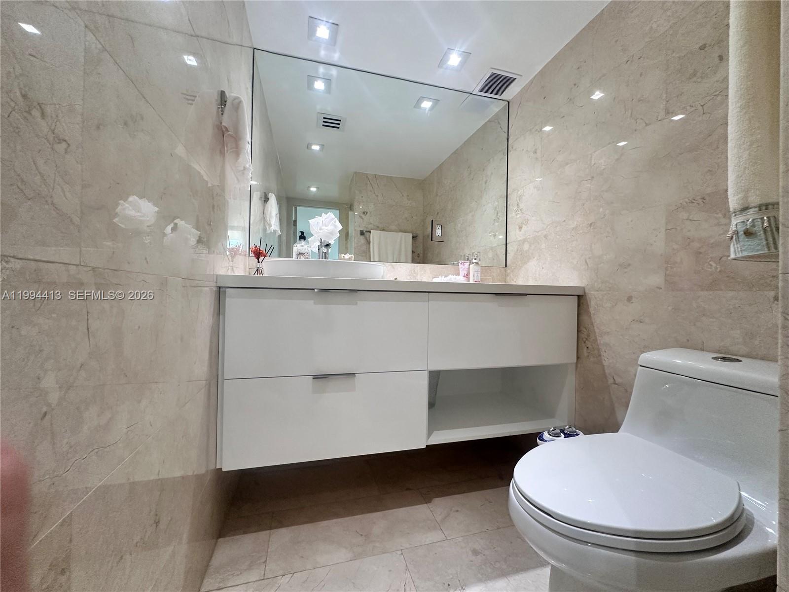 9225 Collins Avenue, Unit 1111 Surfside, FL 33154 - Photo 20 of 54 a bathroom with a toilet sink and mirror