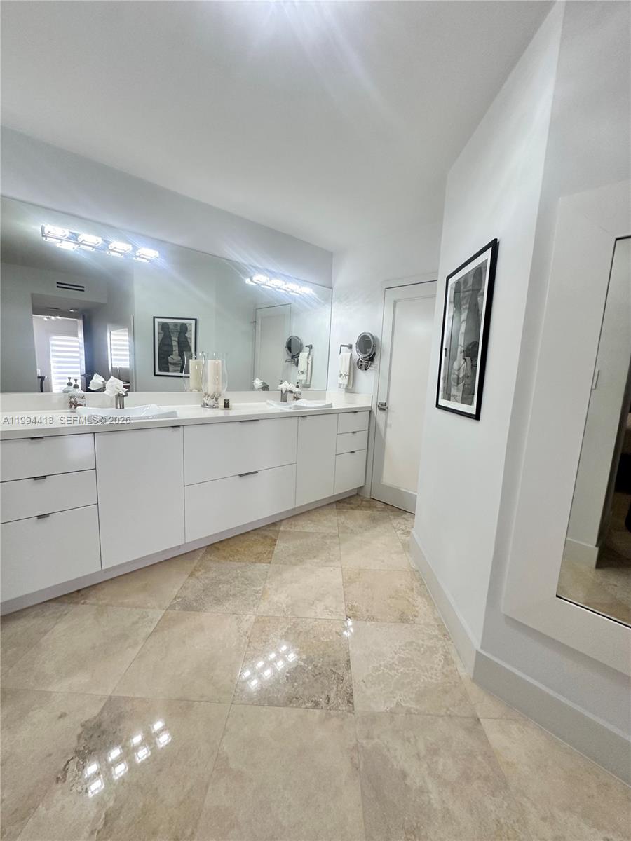 9225 Collins Avenue, Unit 1111 Surfside, FL 33154 - Photo 29 of 54 a large white kitchen with a sink and cabinets